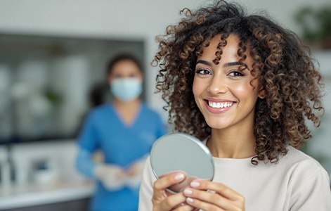 Patient smiling while holding small mirror