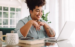 Woman smiling while working on laptop at home