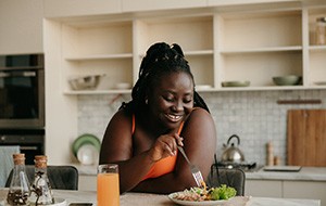 Woman smiling while eating meal in kitchen