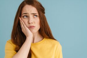 Woman holding jaw on one side. 