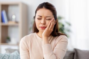Woman holding side of face in pain.