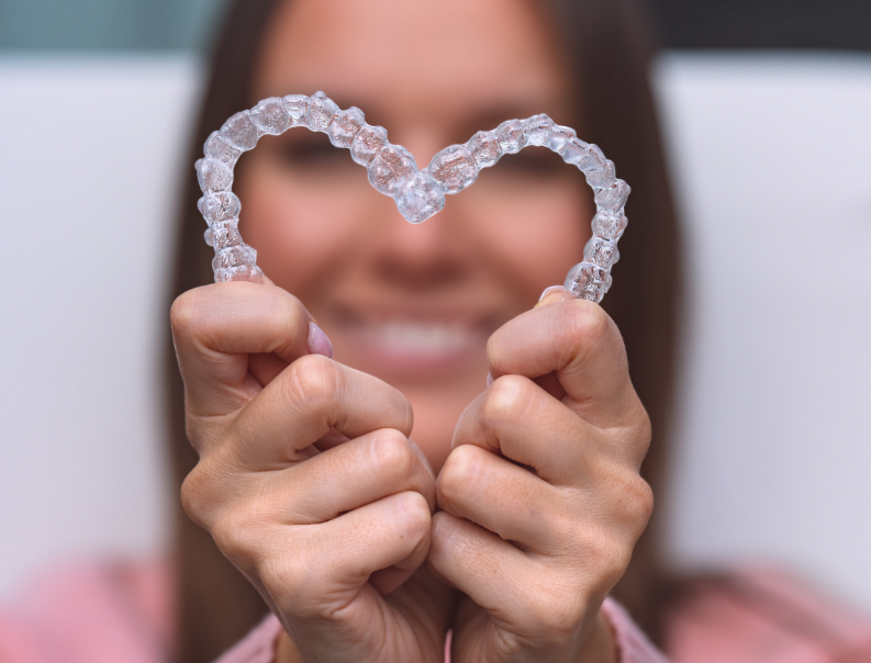 Woman holding clear aligners in heart shape