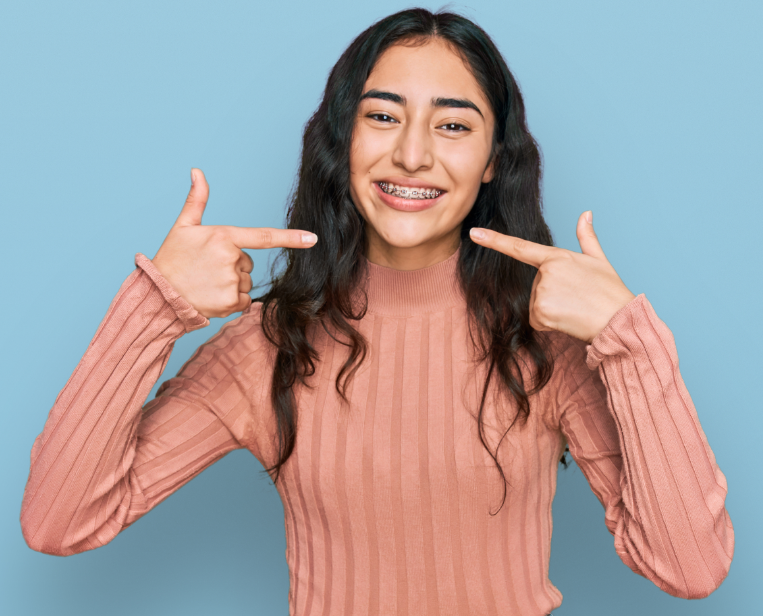 Teen with braces pointing at smile